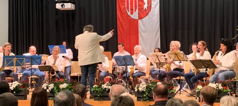 Die Band spielt der Dirigent gibt den Ton an auf der Bühne in der Mensa der Realschule - 300 Gäste kamen Ende Januar ins Bildungszentrum Meckenbeuren zum Bürgerempfang. Als Ehrengäste begrüßte Georg Schellinger MdB Volker Mayer-Lay, die Mitglieder des Landtages August Schuler und Klaus Hoher, den Ersten Landesbeamten des Bodenseekreises Christof Keckeisen, Bürgermeister a.D. Roland Weiß und Bürgermeisterin a.D. Elisabeth Kugel und Mitglieder des Gemeinderats. Er hieß außerdem Vertreterinnen und Vertreter der umliegenden Gemeinden, aus der Wirtschaft, den Verbänden, den lokalen Vereinen und den Kirchengemeinden, Schulen und KiTas herzlich willkommen.