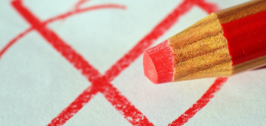 Roter Stift macht rotes Kreuz auf einen Wahlzettel